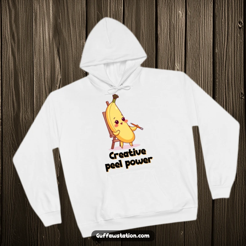 Comfortable funny hoodie featuring a blushing banana painting its portrait with its peel, embodying creative humor.
