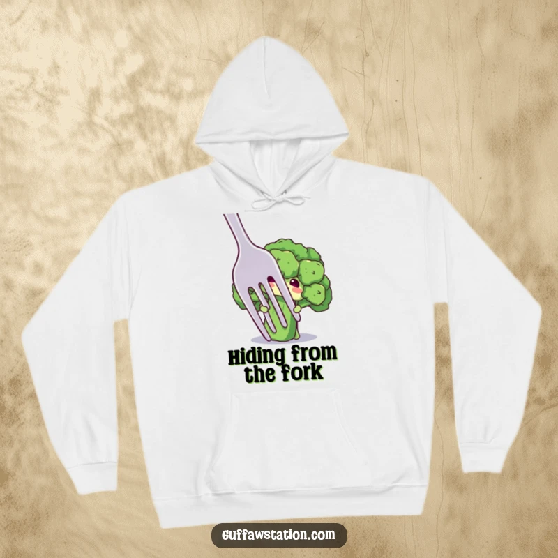 Funny hoodie with a shy broccoli floret character peeking from behind a giant fork, radiating cozy and endearing humor.